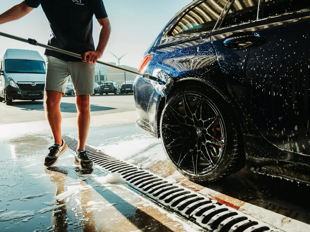 A pressure washer rinsing a car