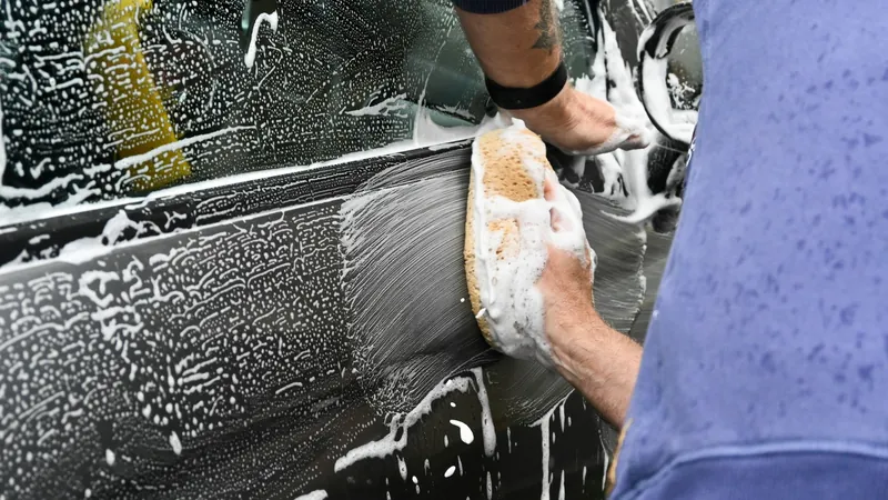 Hands washing a car through thick foam