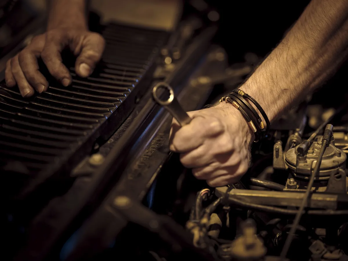 Hands with a wrench working on an engine