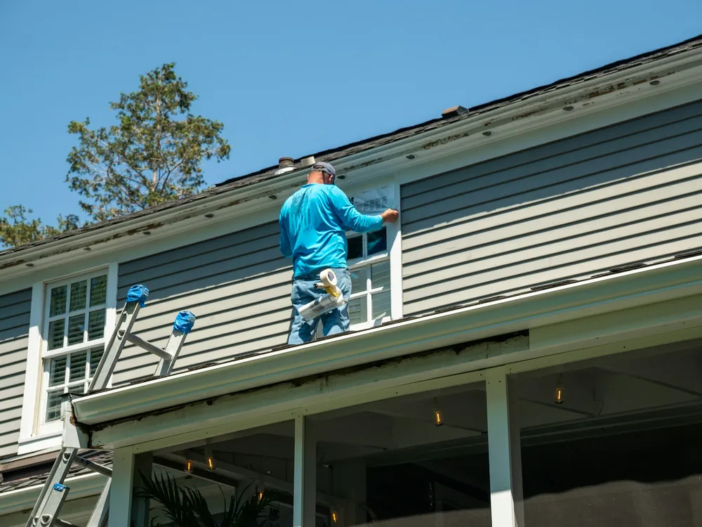 A worker on a ladder at a house