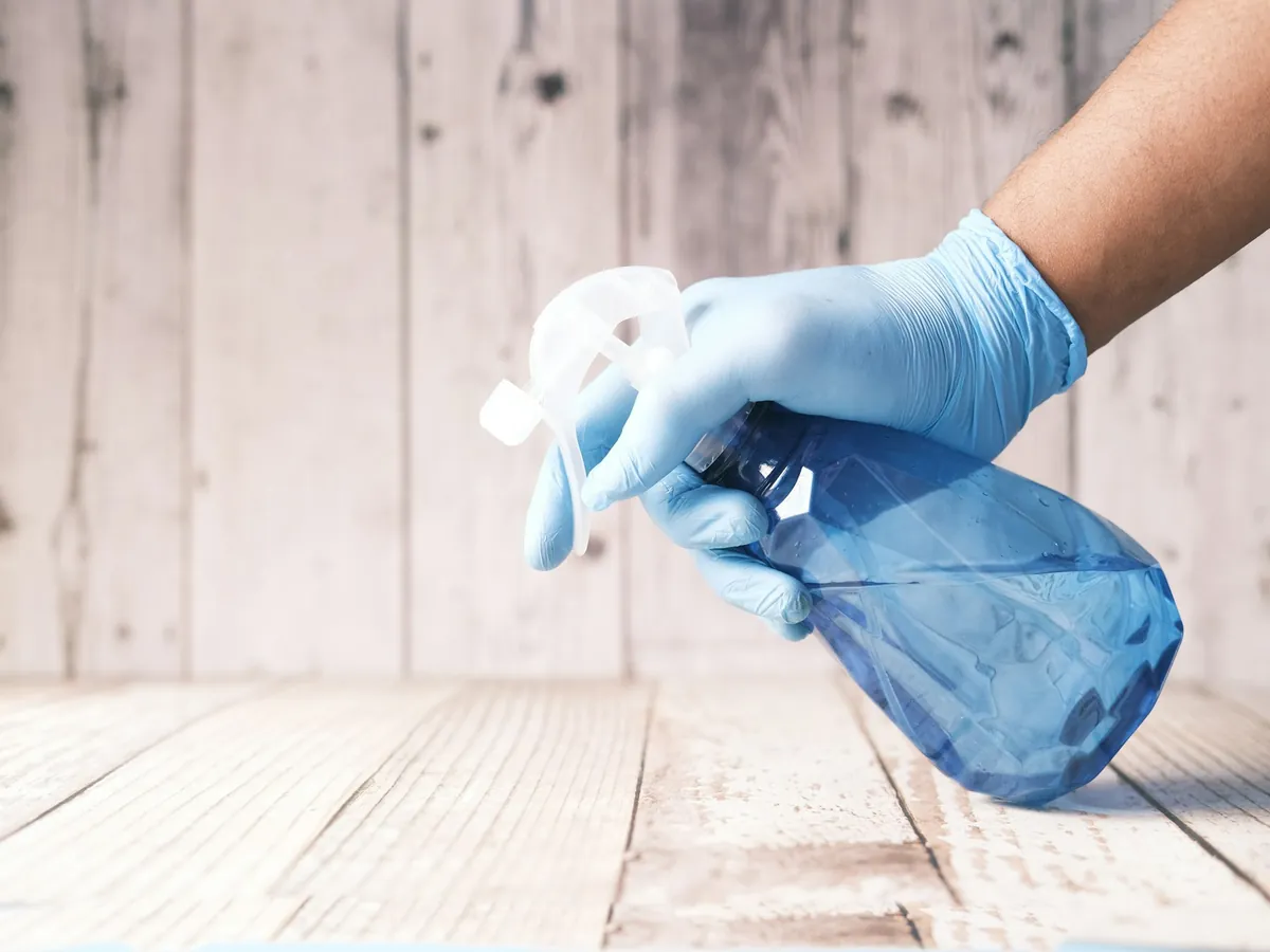 A gloved hand holding a spray bottle