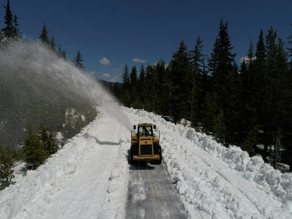 A plow truck on a snowy road at dusk