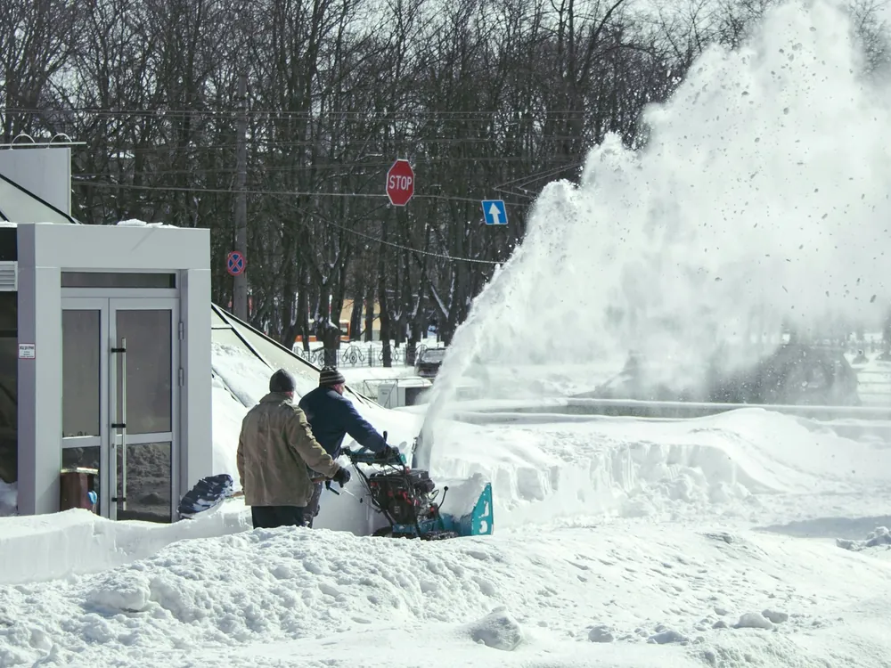 A snow blower clearing a sidewalk