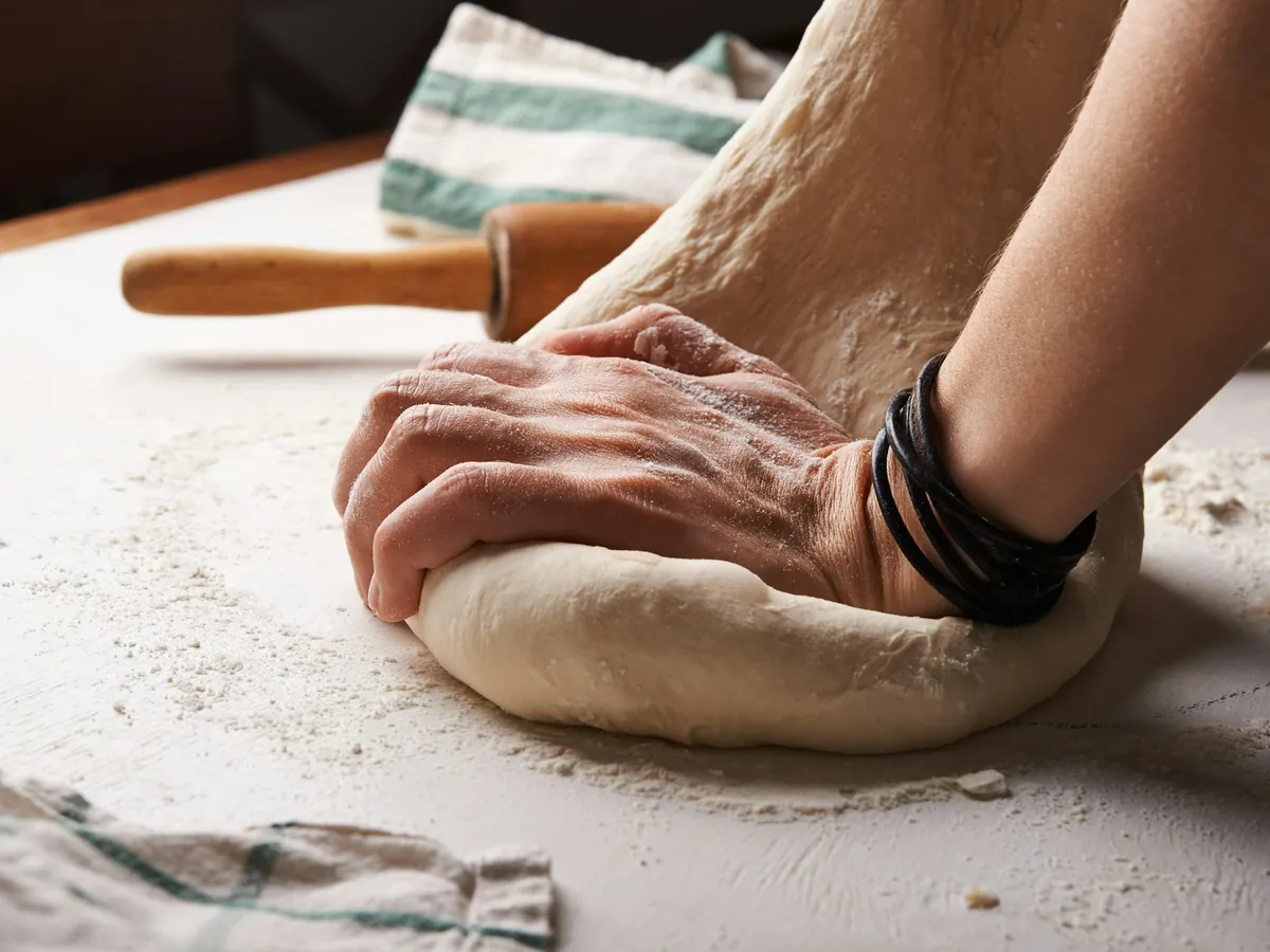 Hands kneading dough on a floured table
