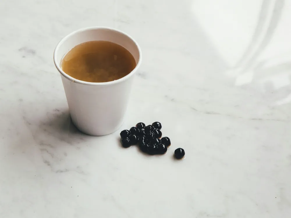 A white cup beside dark pearls