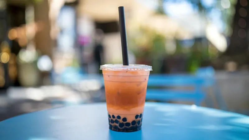 A pink bubble tea with tapioca pearls in a plain cup