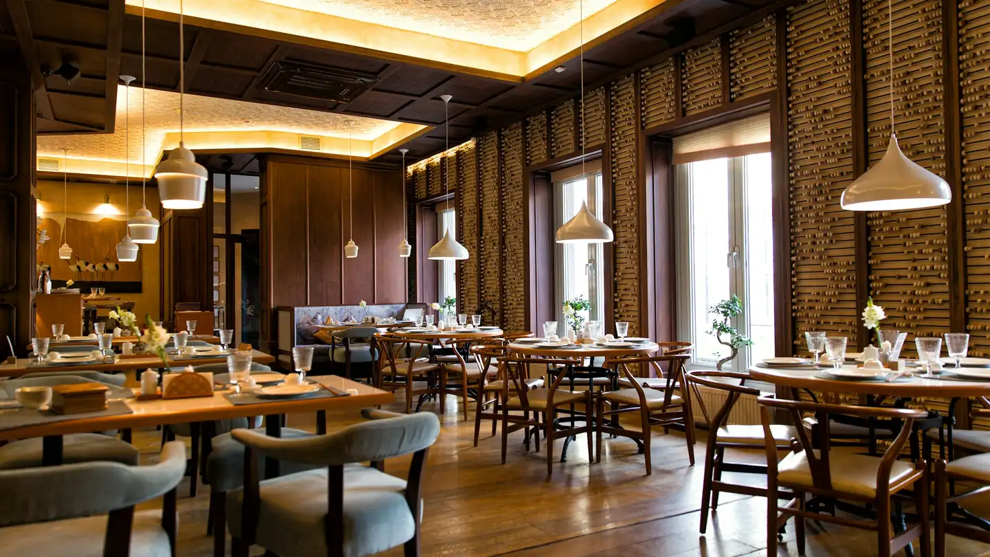 A dining room with wooden tables under warm pendant lights
