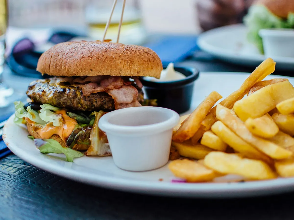 A burger with fries and a dip on a plate