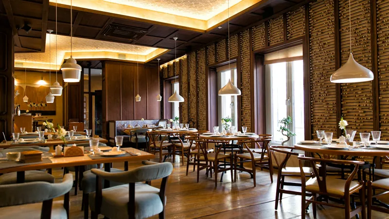 A dining room with wooden tables under warm pendant lights