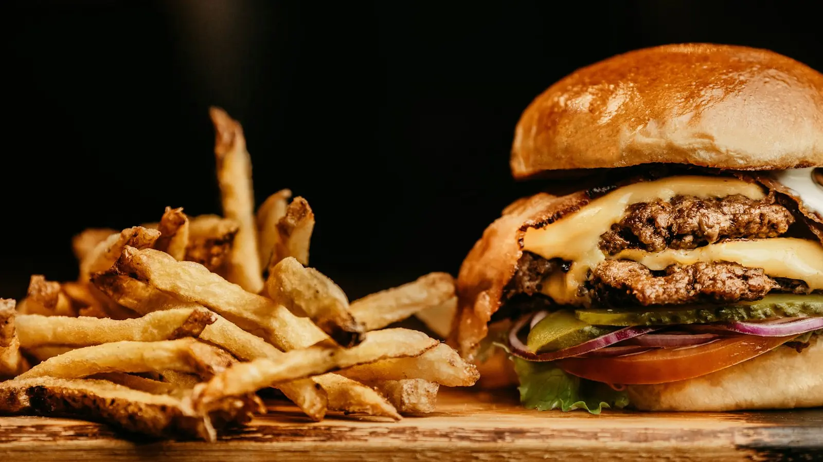 A burger with fries on a board
