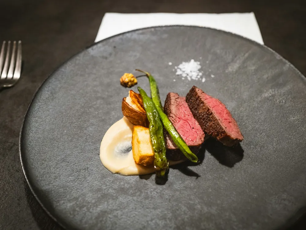 Sliced meat with vegetables on a dark plate