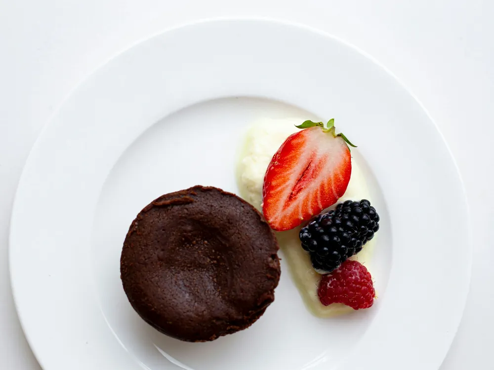 A chocolate dessert with berries on a white plate