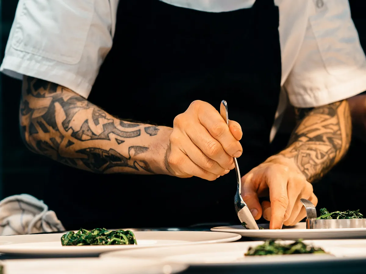 A cook's hands plating a dish