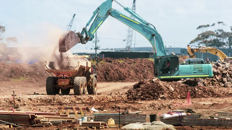 An excavator loading soil into a dump truck