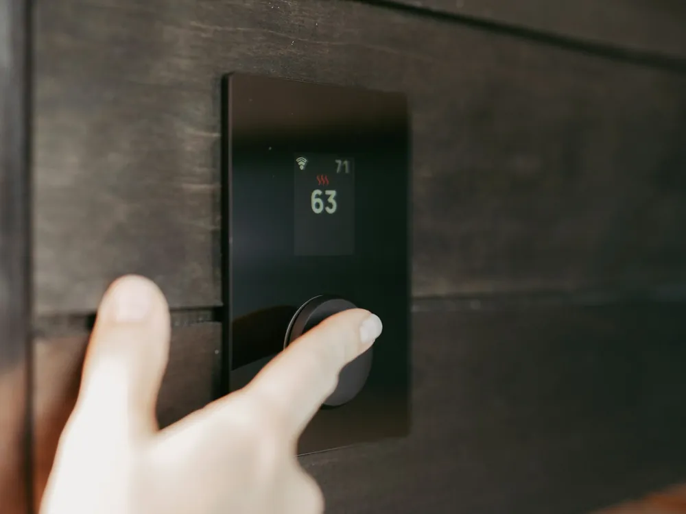 A hand adjusting a digital thermostat