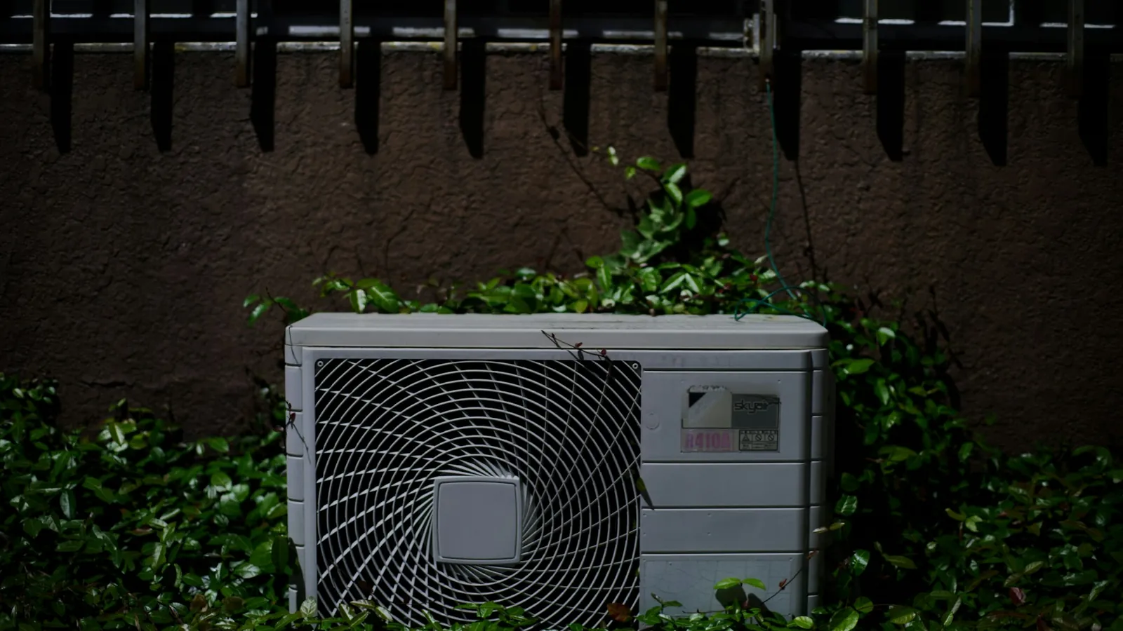 An outdoor air conditioning unit against a hedge