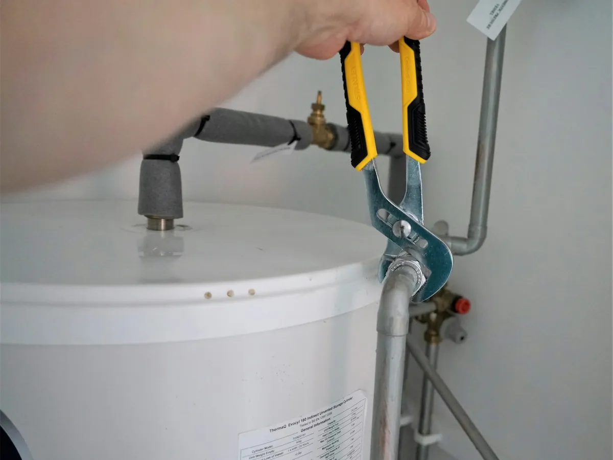Hands tightening a fitting with pliers